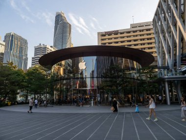 Bangkok, Tayland 'da bir Apple mağazası, insanlar yakınlarda dolaşırken cam cephesinde yansımaları var..