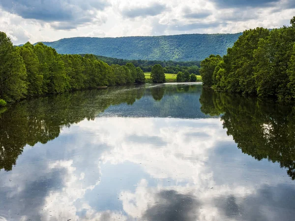 Virginia, ABD 'deki Shenandoah Nehri' nin güney çatalı, ağaçlar, gökyüzü, bulutlar ve uzak dağları yansıtan sakin sularla övünür..