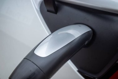 Yeni ulaşım çağı. Bir arabaya güvenli bir şekilde takılmış elektrik şarj aletinin sapının yakın görüntüsü..