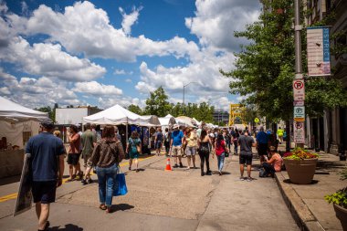 Pittsburgh şehir merkezindeki sanat festivalinin canlı atmosferinin tadını çıkarın. Güneşli bir yaz gününde ikonik sarı köprünün arka planına karşı insanlarla dolu..