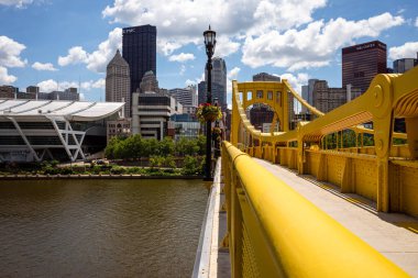 Sunny Pittsburgh: Blue sky & white clouds over vibrant downtown and yellow Rachel Carson Bridge. clipart