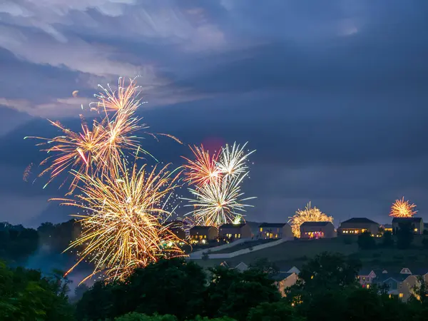 stock image A dazzling display of fireworks illuminates the summer night sky, bursting with color and light above a quiet residential area in the USA, capturing the essence of celebration.