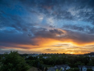 A breathtakingly colorful sunset lights up the summer sky, casting vivid hues over suburban homes in Pennsylvania, USA, turning the evening into a masterpiece of nature's artistry. clipart