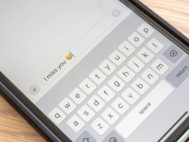 A close-up photo of a smartphone screen displaying a text message expressing feelings of loneliness, accompanied by a melancholic emoji. clipart