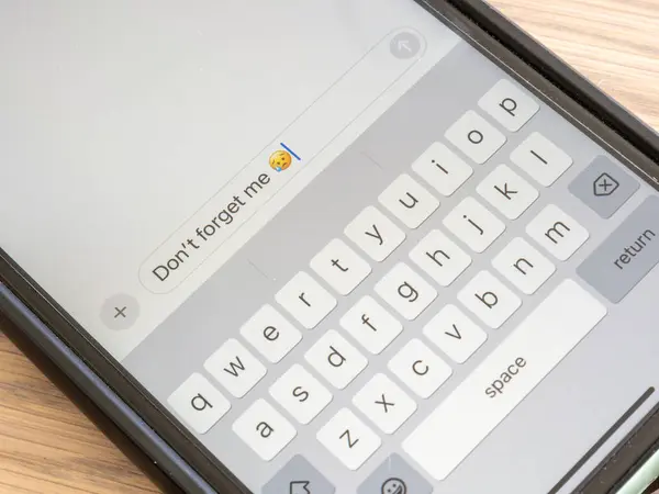 stock image A close-up photo of a smartphone screen displaying a text message expressing a longing for connection, with a melancholic emoji adding to the emotional impact.