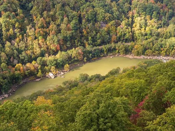 Güneş ışığı, New River Gorge Ulusal Parkı, Batı Virginia 'daki suların üzerindeki rengarenk dağ yamacını vurgular ve çarpıcı bir sonbahar manzarası yaratır..