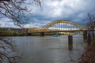 Pittsburgh, Pensilvanya 'daki ikonik sarı 10. Cadde Köprüsü Allegheny Nehri' ni geçer. Altında bir mavna süzülerek şehrin manzarasını sunar..