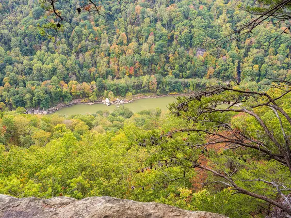New River Gorge Ulusal Parkı 'nda, sonbaharın başlarında nehir derinden akarken dağ kenarlarını boyayarak nefes kesen mevsimsel bir manzara yaratır..