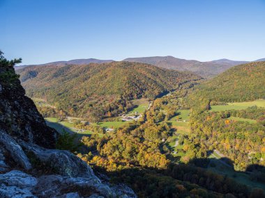 A view from Seneca Rocks reveals vibrant fall colors across the mountains, a clear blue sky, and houses below in West Virginia, USA. clipart