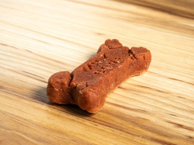 Vibrant red milkbone dog treat displayed on a rustic wooden surface clipart