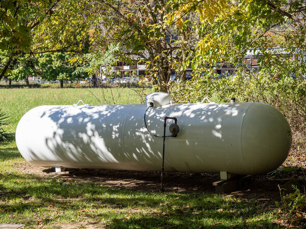 Sunshine bathes a ghostly white propane cylinder in a golden field