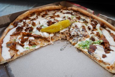 Yarı yenmiş bir donör kebap pizza, kremalı sos damlıyor, keskin bir biber turşusu, hala kutusunda cezbedici..