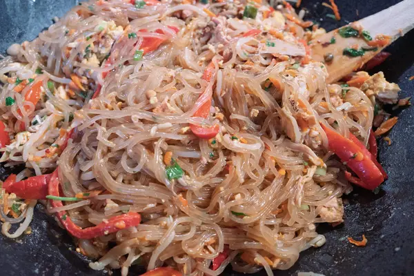 Lezzetli kızarmış cam şehriye, ayrıca selofan erişte olarak da bilinir, renkli sebzeler ve sıcak tavuklu yumuşak tavukla birlikte..