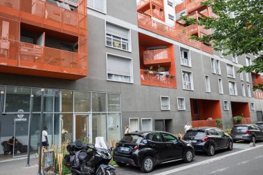 Saint-Ouen, Fransa 'da modern bir konut binası, çarpan turuncu balkonları ve caddelerde park edilmiş arabaları var..
