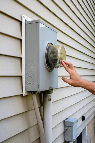 Man looking at electricity meter at home. Electric power box meter for home use, utility bill .