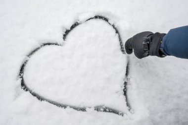 Karda kalp çizen bir adam. Aşkın sembolü. Donmuş soğuk kalp.