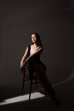 Zarif güzellik konsepti. Güzel makyajlı şık bir bayan. Siyah elbiseli genç kadın, ışık altında poz veriyor.