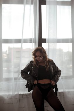 Siyah deri ceketli şık bayan ve cam kenarında poz veren elmas gözlüklü kadın.