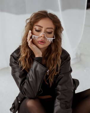 Siyah deri ceketli şık bayan ve cam kenarında poz veren elmas gözlüklü kadın.