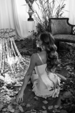 Kurumuş çiçekler ve bitkilerle birlikte yatak odasında poz veren zarif bir kadın.