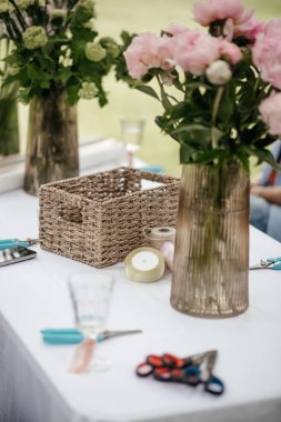 Çiçek vazoları ve buket yapmak için malzeme dolu bir masa.