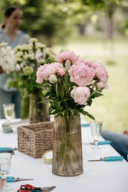 Çiçek vazoları ve buket yapmak için malzeme dolu bir masa.