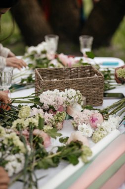 Çiçeklerle dolu bir masa ve buket yapmak için malzeme.