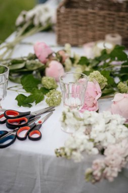 Çiçeklerle dolu bir masa ve buket yapmak için malzeme.