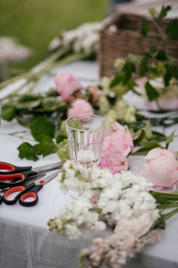 Çiçeklerle dolu bir masa ve buket yapmak için malzeme.