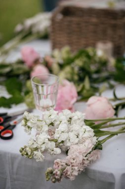 Çiçeklerle dolu bir masa ve buket yapmak için malzeme.