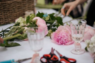 Çiçeklerle dolu bir masa ve buket yapmak için malzeme.