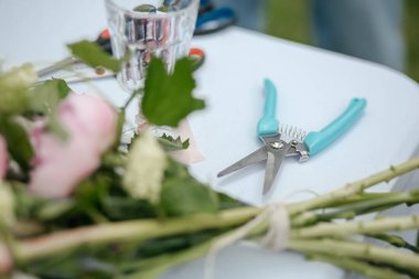 Çiçeklerle dolu bir masa ve buket yapmak için malzeme.