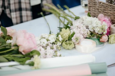 Çiçeklerle dolu bir masa ve buket yapmak için malzeme.