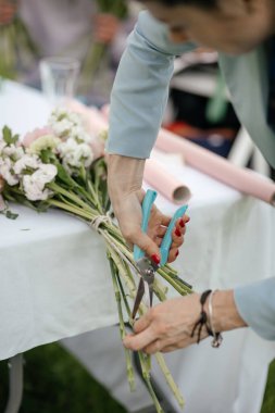 Kapalı - düğün buketi için çiçek kesen kadın elleri.