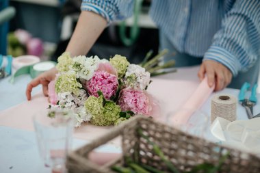Çiçekçi, çiçekçide çiçek buketi paketliyor.