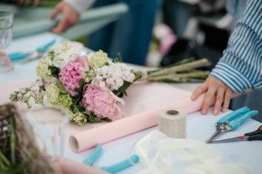 Çiçekçi, çiçekçide çiçek buketi paketliyor.