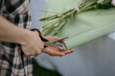 Kadınların ellerini kapatın. Masadaki çiçekler için ambalaj kağıdı kesin.