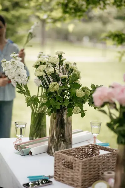 Çiçek vazoları ve buket yapmak için malzeme dolu bir masa.