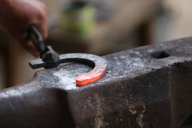  Demirci dövmesi sertleştirme ve ısıtma demiri. Demirci atölyesinde çalışıyor. Smith eski moda bir at nalı yaptı. 