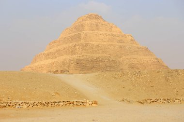Panoramic view of Stepped Pyramid of Djoser at Saqqara Egypt on a foggy morning under clouds clipart