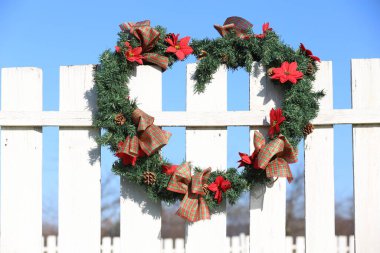 Kırsal hayvan çiftliğinin çitlerinde asılı güzel bir Noel çelengi. Harika el yapımı Noel dekorasyonu. 