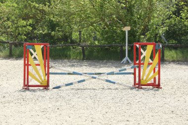 Atlama direklerini, engelleri, engelleri göster. Atlama eğitiminde yarışçıları bekle. Yaz mevsiminde dışarıda at yarışı kursu. Binicilik etkinliği için kumda kutuplar