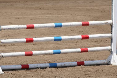 Atlama direklerini, engelleri, engelleri göster. Atlama eğitiminde yarışçıları bekle. Yaz mevsiminde dışarıda at yarışı kursu. Binicilik etkinliği için kumda kutuplar
