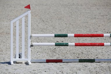 Atlama direklerini, engelleri, engelleri göster. Atlama eğitiminde yarışçıları bekle. Yaz mevsiminde dışarıda at yarışı kursu. Binicilik etkinliği için kumda kutuplar