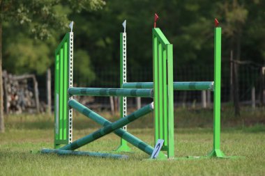 Atlama direklerini, engelleri, engelleri göster. Atlama eğitiminde yarışçıları bekle. Yaz mevsiminde dışarıda at yarışı kursu. Binicilik etkinliği için kumda kutuplar