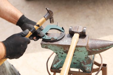 Çiftçi aletleri kırsal at çiftliğinin görüş açısını kapatıyor. Binicilik geçmişi. Teçhizat ve çekiç eski örsün üzerinde..