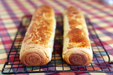 Composition of homemade walnut and poppy seed rolls aka beigli in Hungary. Traditional hungarian christmas or easter cake bejgli at christmastime. Freshly baked sweet filled strudel cakes on checkered tablecloth background  clipart