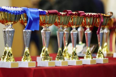 Bir grup parlak altın kupa arka arkaya yarışmacıları ve kazananları bekliyor. Spor arkaplanı