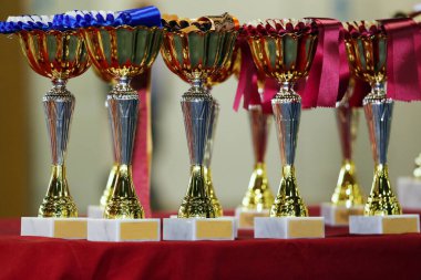 Bir grup parlak altın kupa arka arkaya yarışmacıları ve kazananları bekliyor. Spor arkaplanı