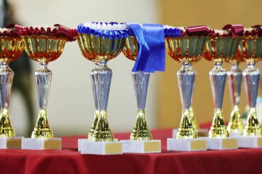 Bir grup parlak altın kupa arka arkaya yarışmacıları ve kazananları bekliyor. Spor arkaplanı